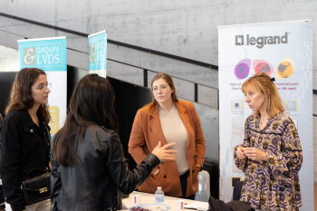 Quatre personnes sont debout et discutent autour d'un stand lors de la journée des Métiers du Chiffre organisée par l'IAE Limoges.