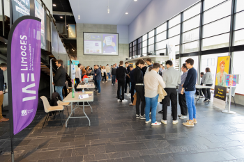 Des étudiants sont réunis dans un couloir d'université et des stands sont disposés autour d'eux lors de la journée des métiers du chiffre organisée par l'IAE Limoges.