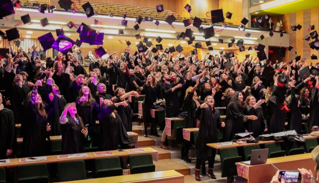 Des étudiants de l'IAE Limoges sont rassemblés dans un amphithéâtre et sont en train de jeter leurs chapeaux.